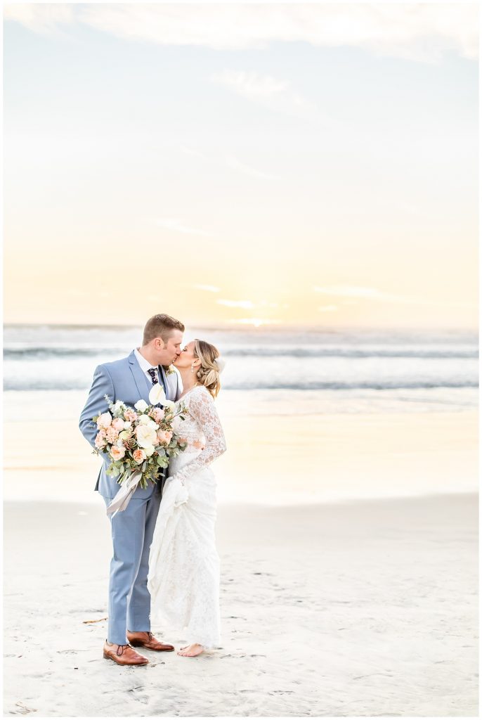 couple kissing on the beach on their wedding day