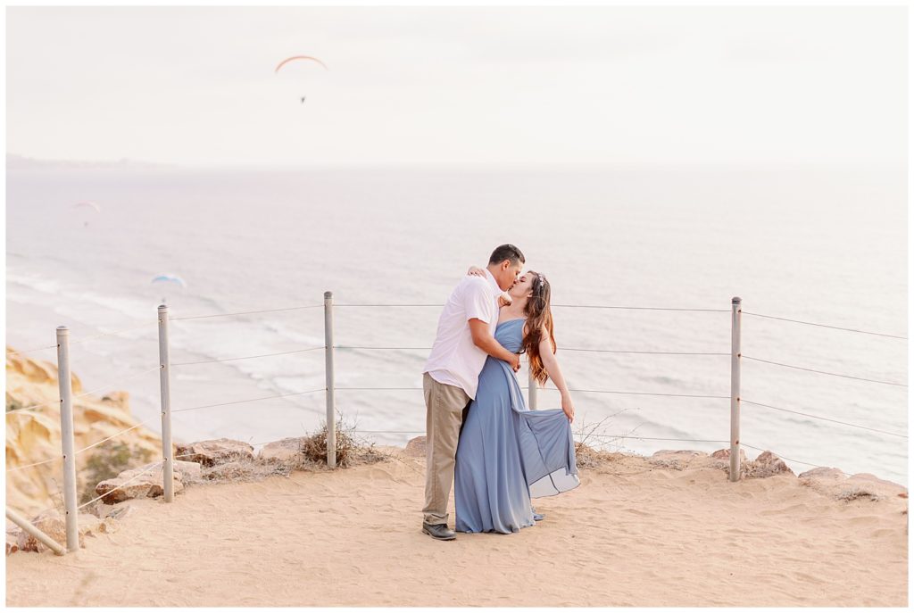 Couple kissing on a hill on the beach in Torrey pines beach, CA