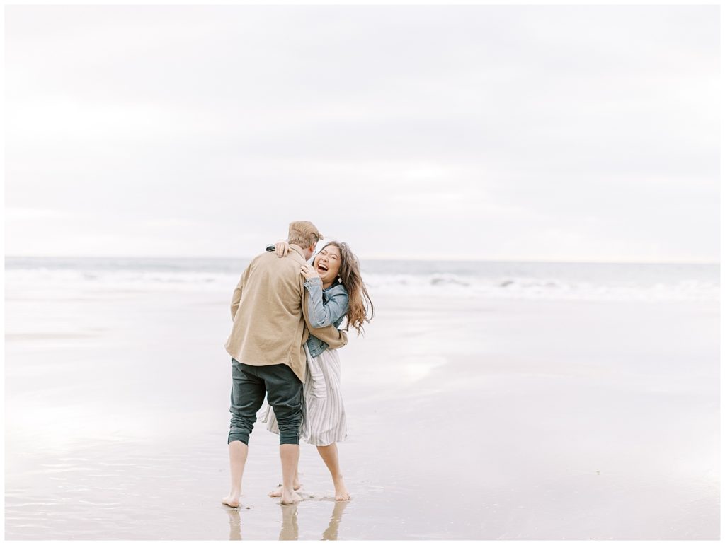 couple on the beach by the ocean embracing each other and laughing