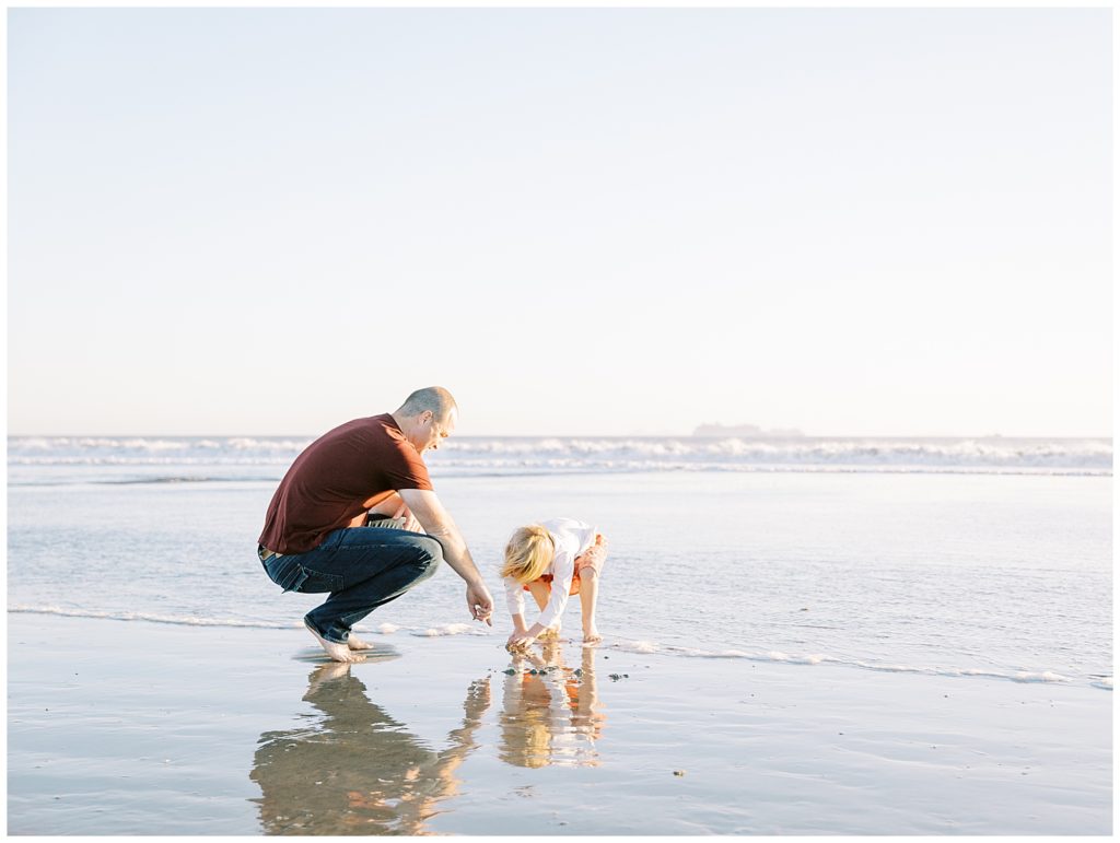 dad and daughter play in the ocean during their family photo session