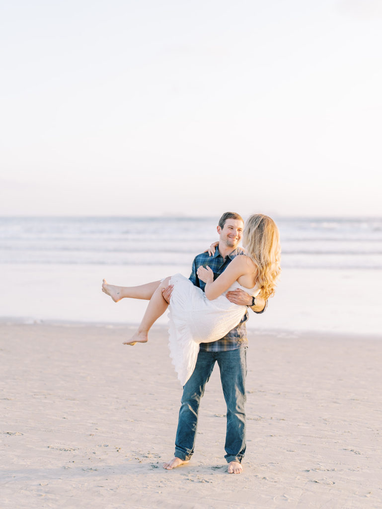 guy holding girl on the beach 