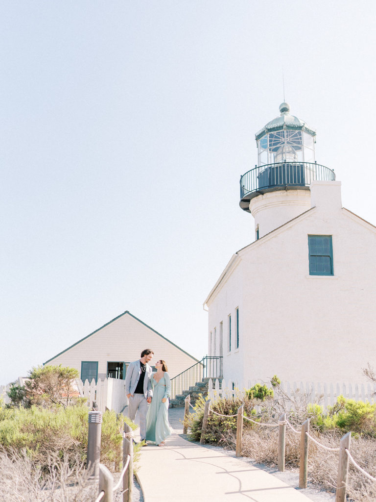 couple walking and holding hands in front of the Old Point Loma Lighthouse 