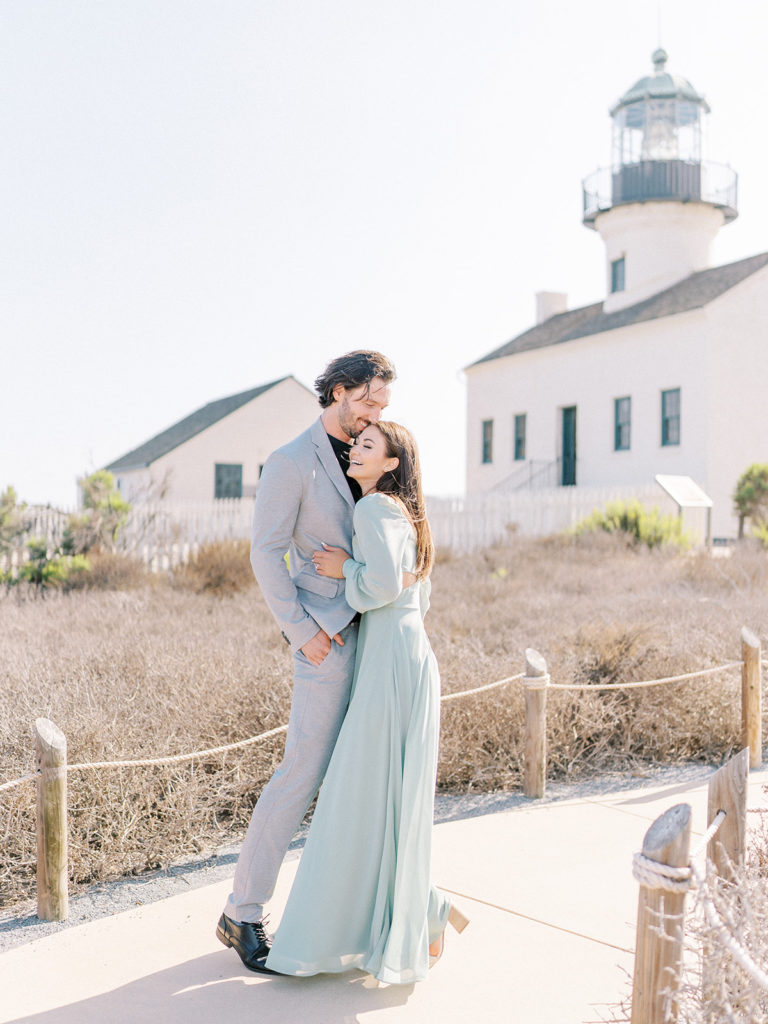 couple embracing each other and laughing in front of the Old Point Loma Lighthouse 