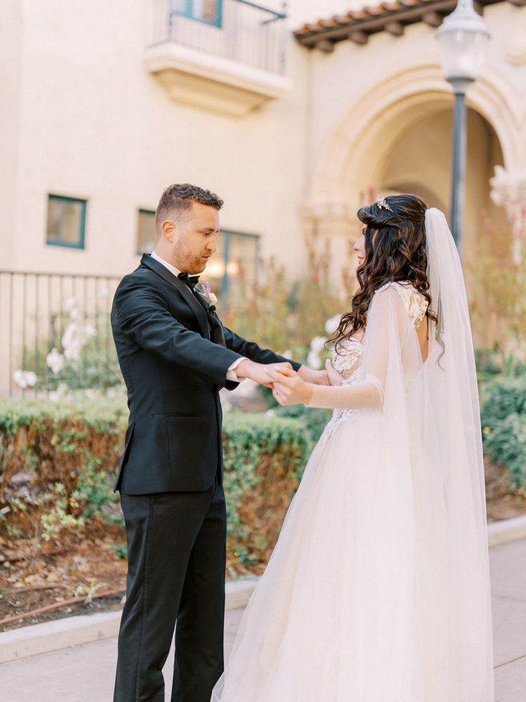 bride and groom holding hands during first look at Balboa park for their Prado wedding 