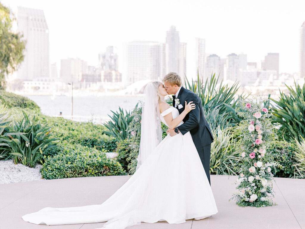 bride and groom kissing with the San Diego skyline as backdrop