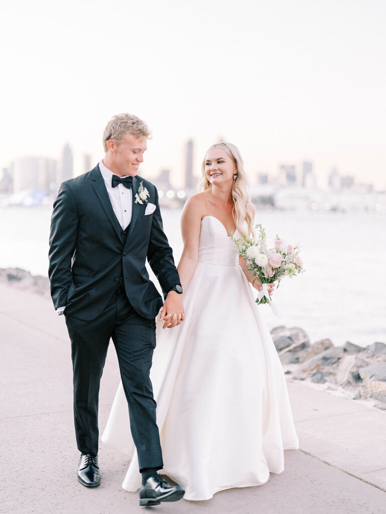 bride and groom walking with the San Diego skyline as backdrop