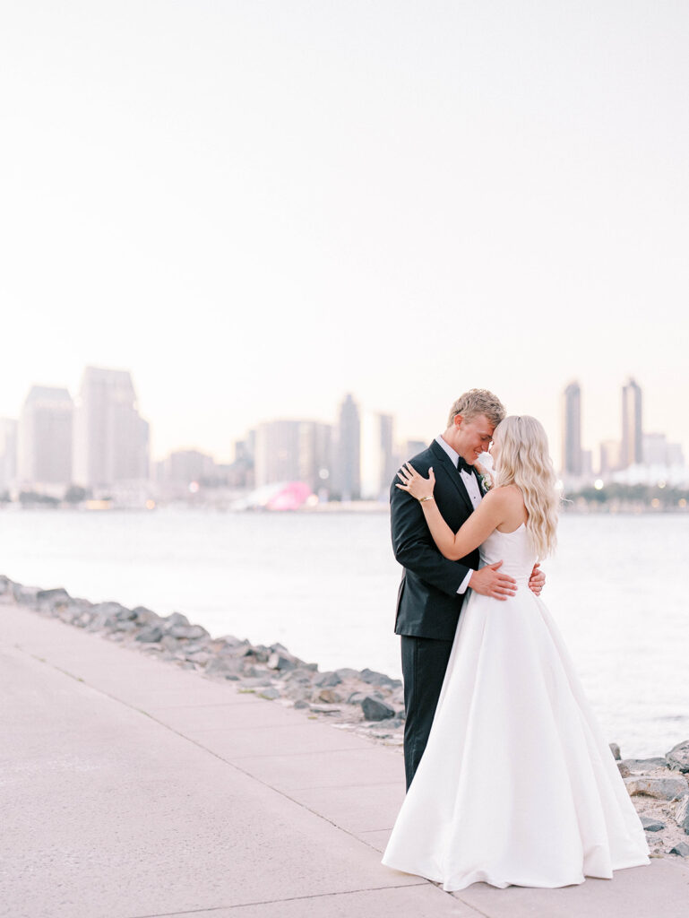 bride and groom embracing with the San Diego skyline as backdrop