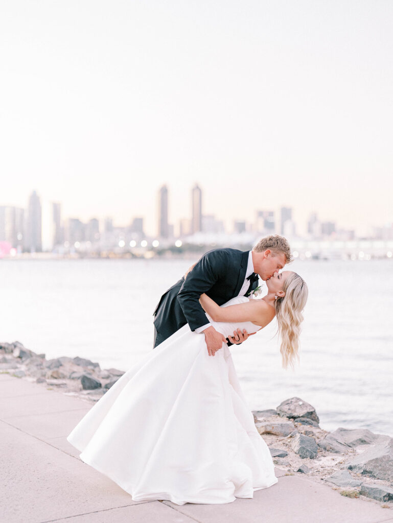 bride and groom kissing with the San Diego skyline as backdrop