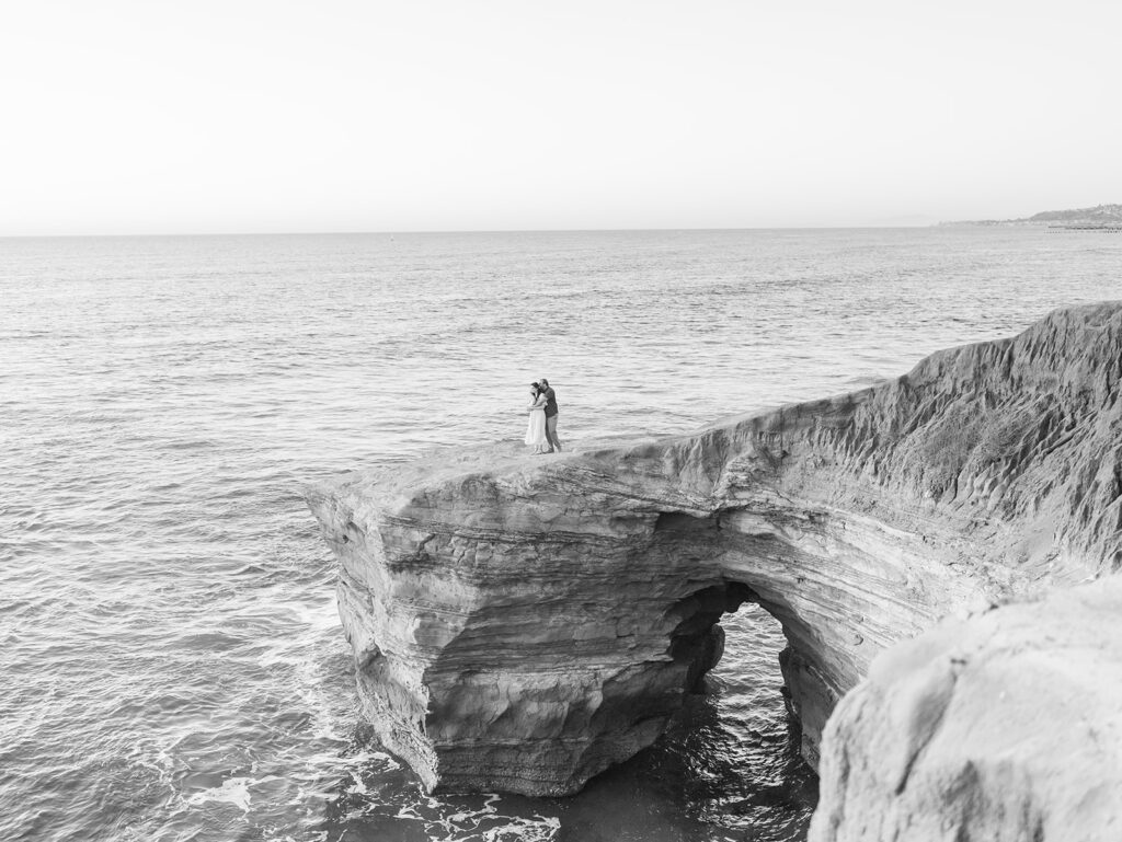 Cliffside overlooking the ocean in sunset cliffs with couple during sunset in black and white