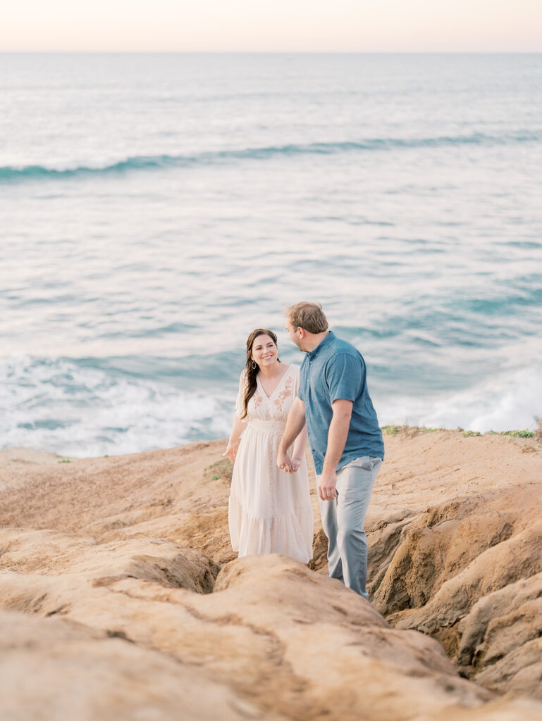 Cliffside overlooking the ocean in sunset cliffs with couple walking up cliff during sunset