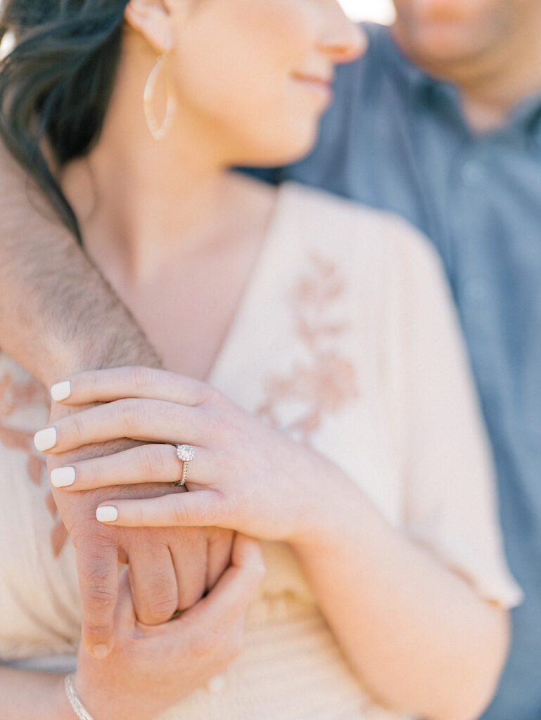 closeup of a couple holding hands with the focus on the engagement ring
