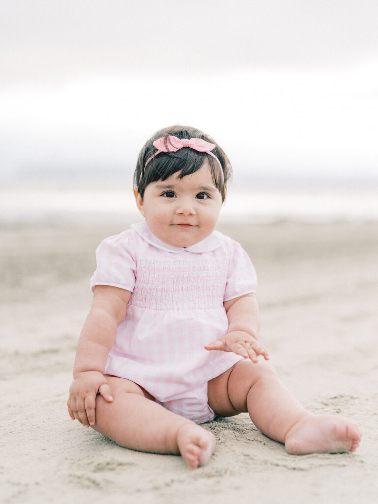 A toddler seated on the sand at Coronado Beach