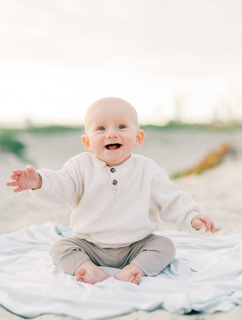 A toddler smiling while sitting on sand