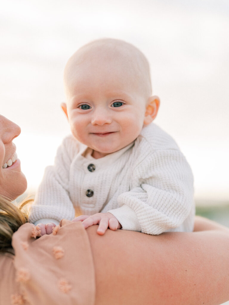 A toddler smiling while her mother is carrying her