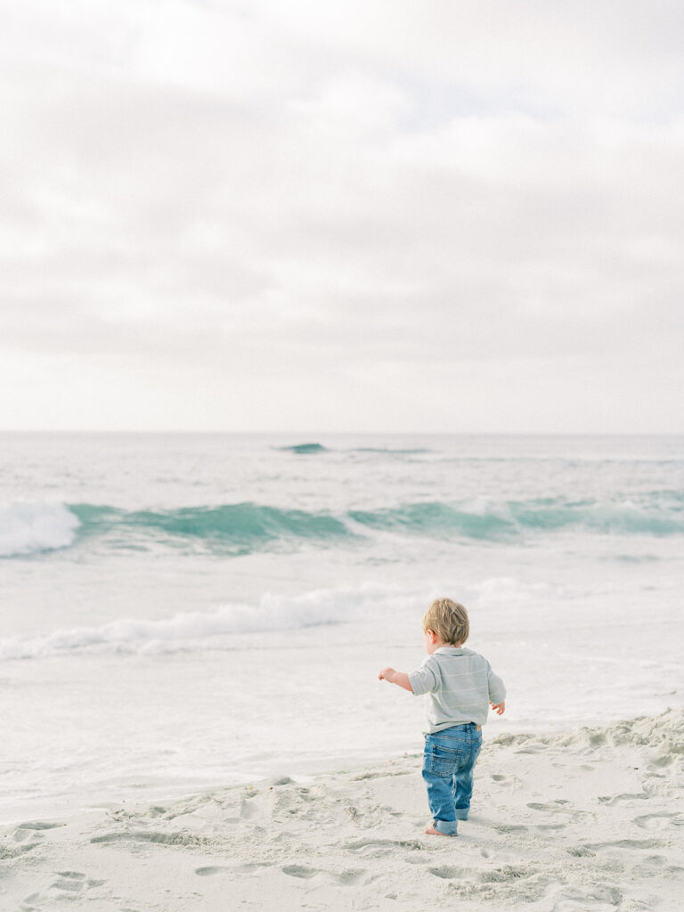 A toddler walking towards the water