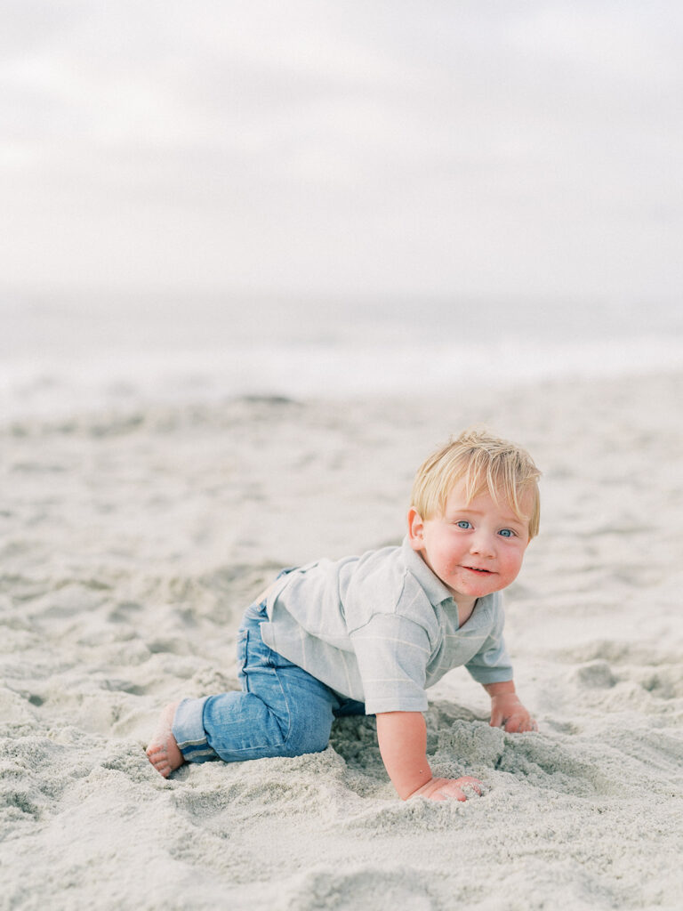 A toddler crawling on the sand during La Jolla family photography session