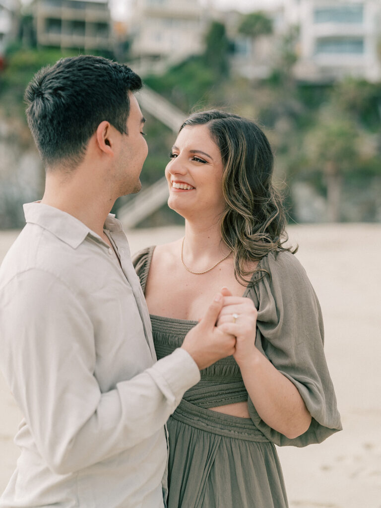 A woman beams with happiness as she gazes at her fiancé at Laguna Beach