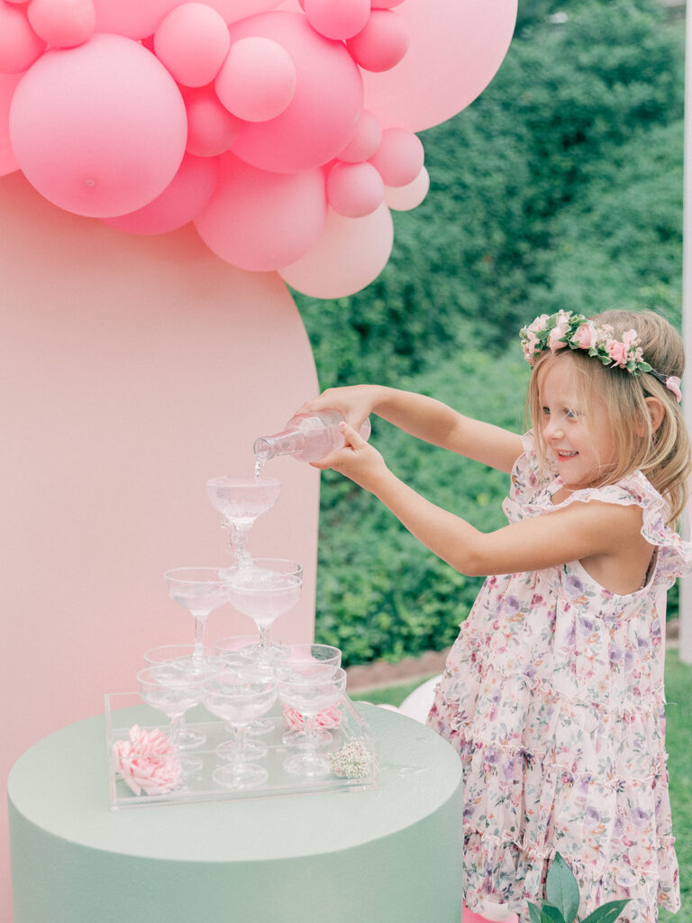 a little girl pouring a drink to a champaign tower