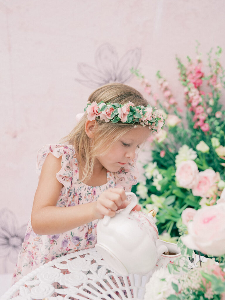 a little girl pouring a tea into a teacup