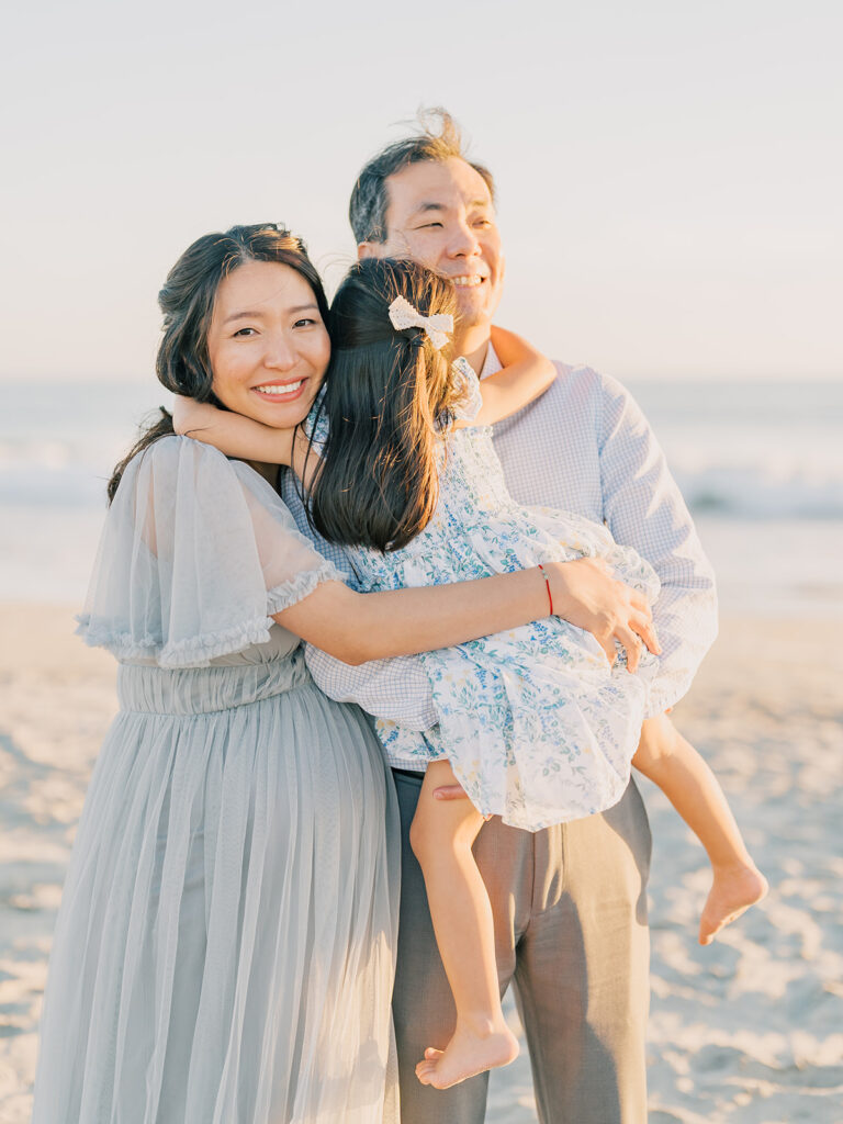 A kid hugging her parents captured by maternity photographer in San Diego