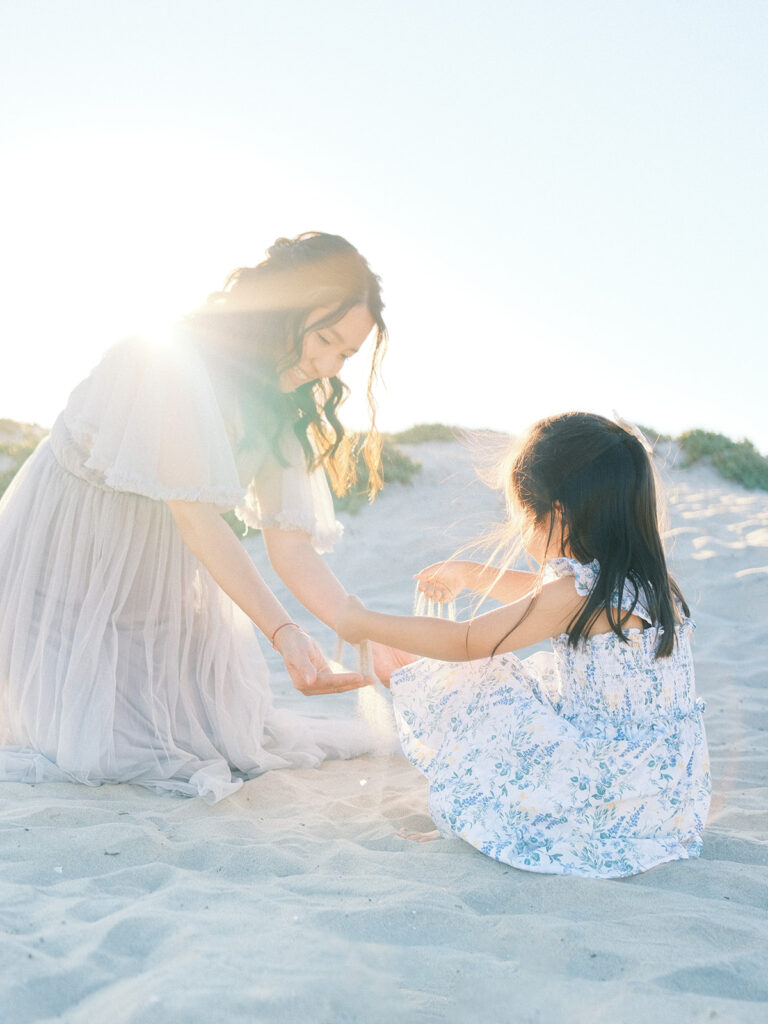 Mother and daughter sitting on the sand at Coronado Beach captured by San Diego maternity photographer