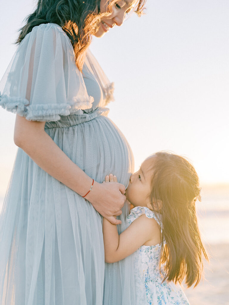 A kid kissing her pregnant mother's tummy