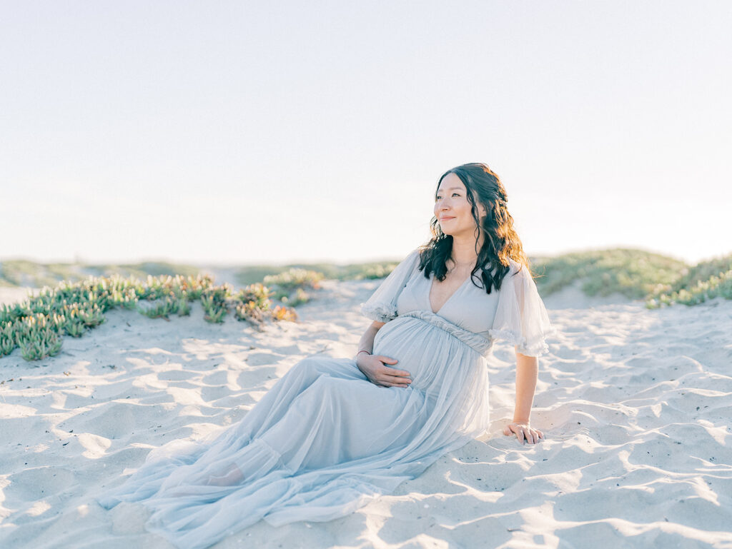 Mom to be sitting on the sand at Coronado Beach