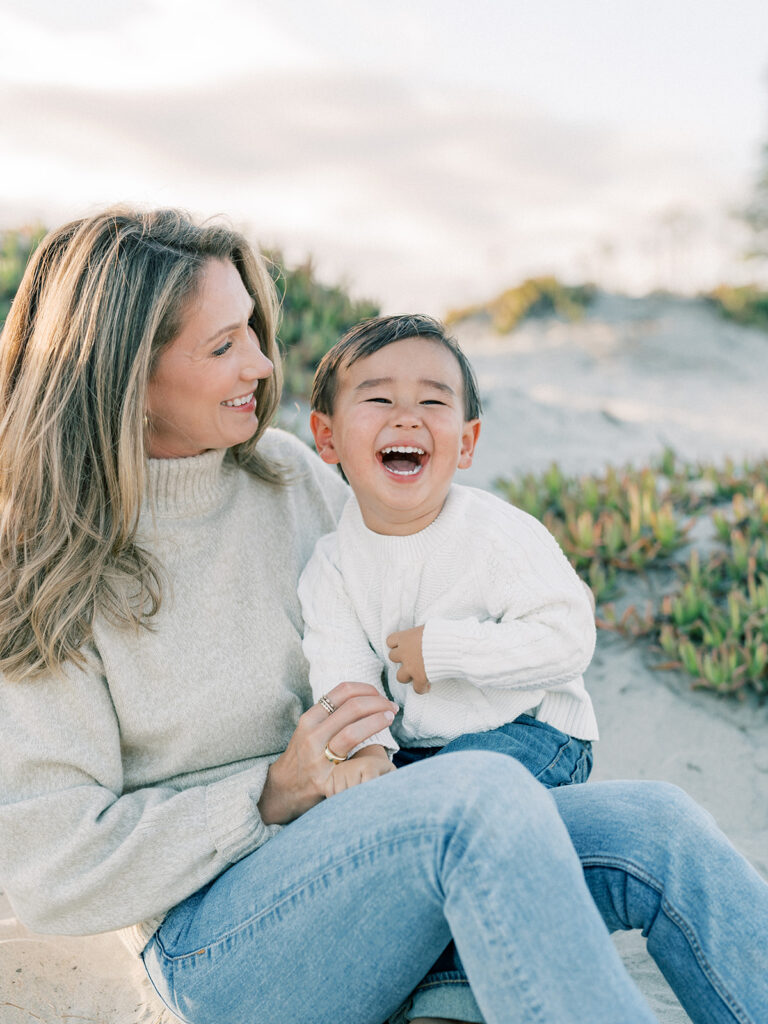 a toddler laughing while his mother is holding him