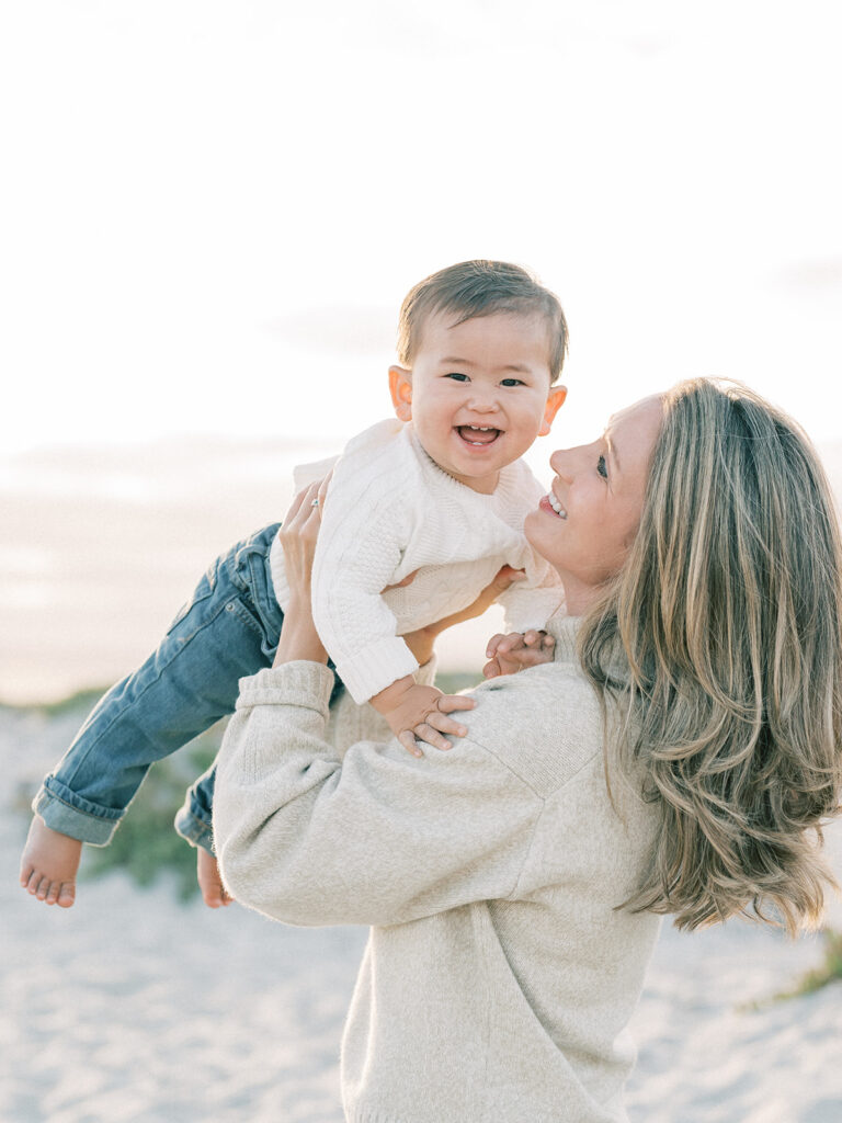 a mother tosses her toddler during their family session at coronado beach san diego 