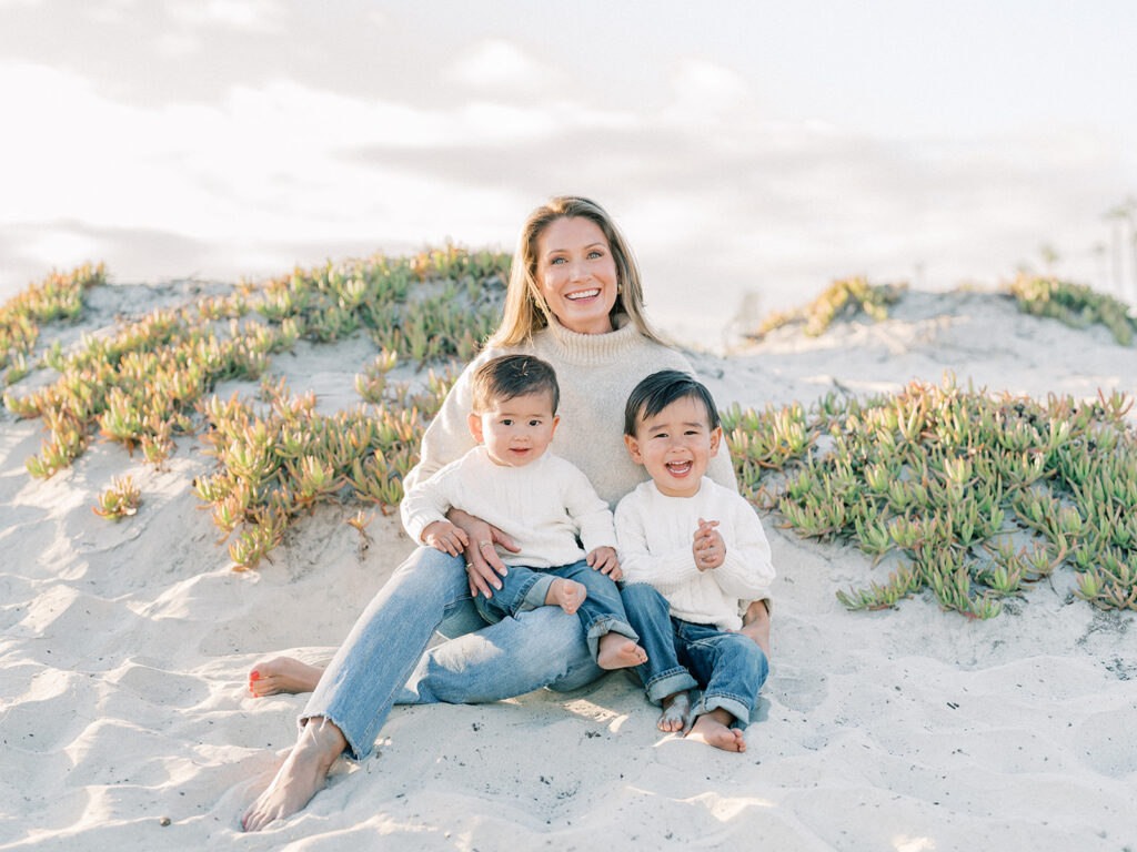 a mother and her sons sitting side by side on a sandy coronado beach in san diego