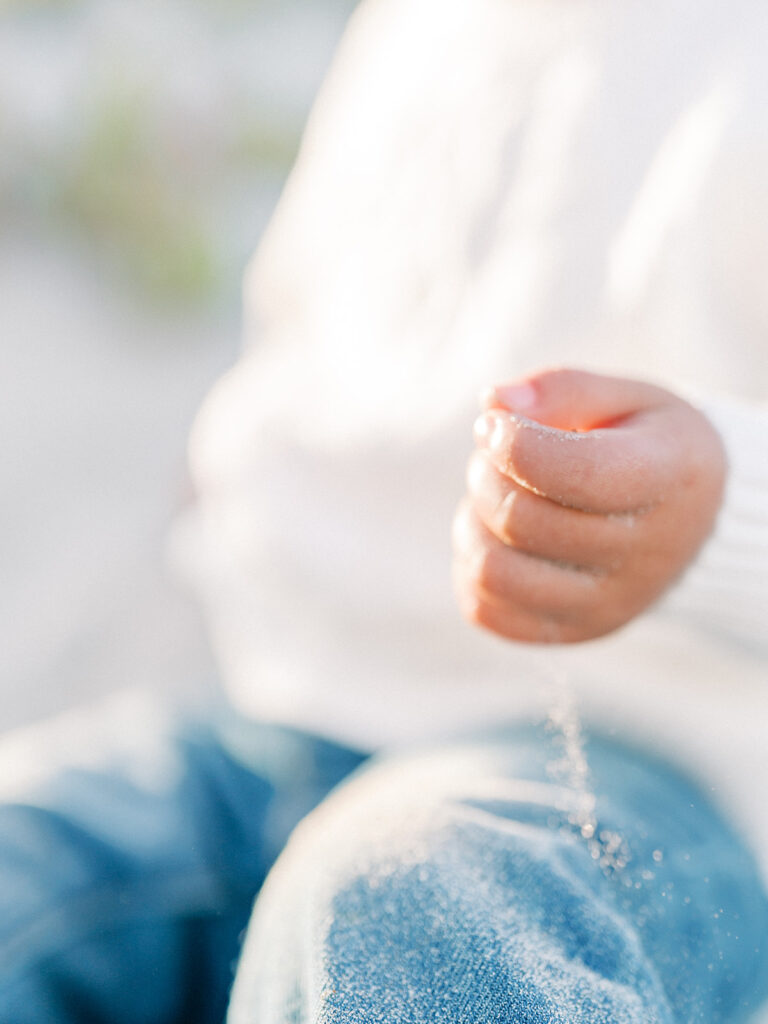 a photo of little hand playing with the sand