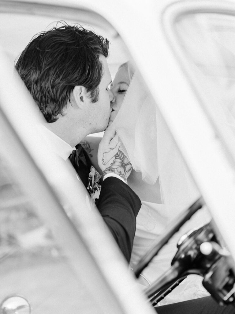 black and white photo of a couple kissing in a vintage car