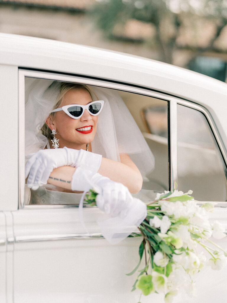 a bride smiling while holding a bouquet inside of a vintage car