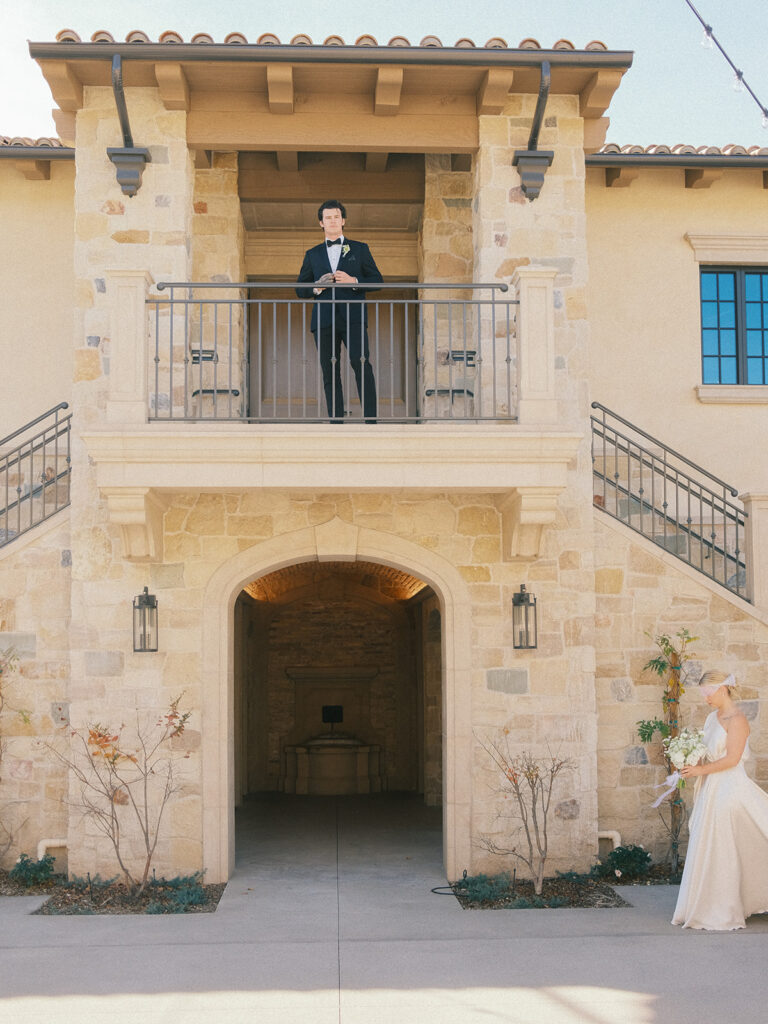 a groom at the veranda and a bride walking down