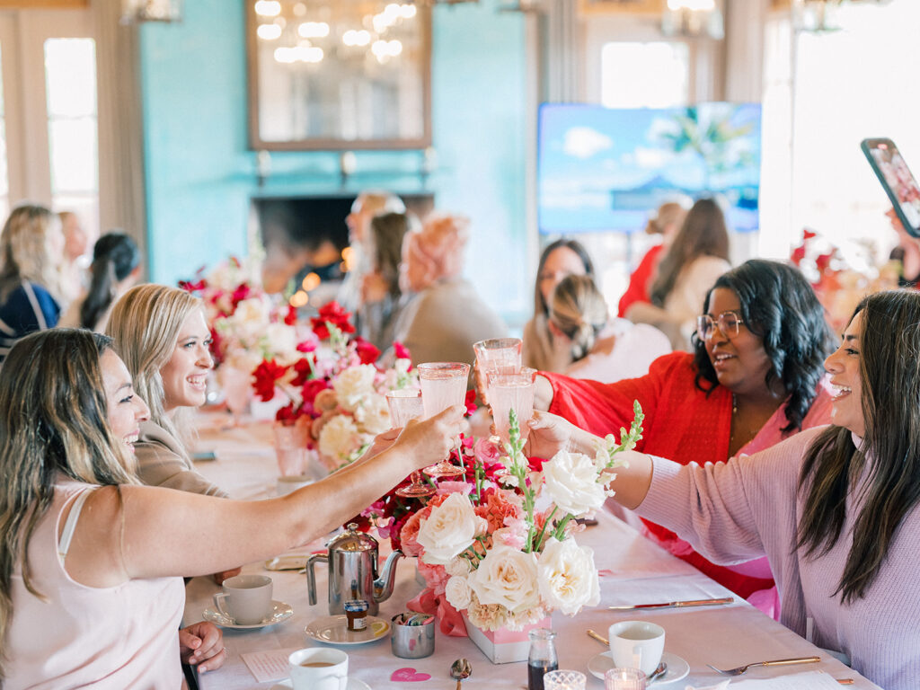 four woman doing a toast while smiling