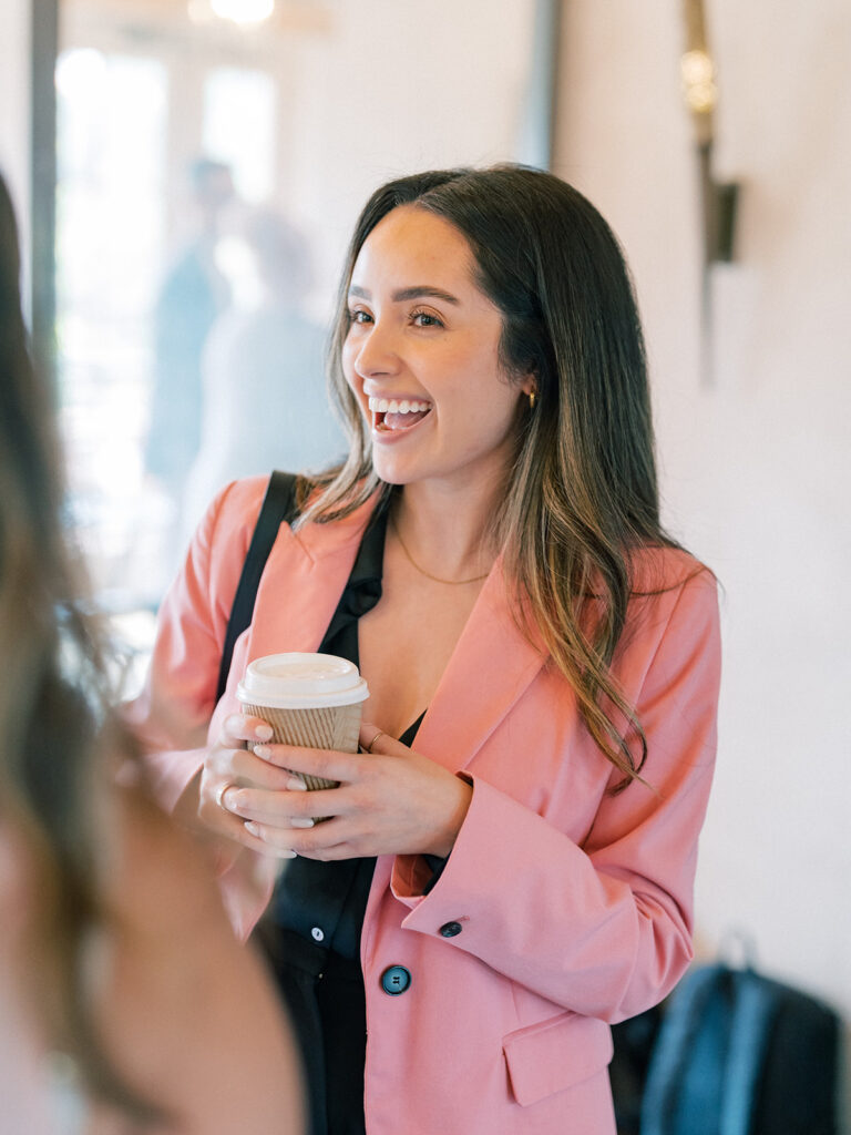 a woman smiling while holding a cup of coffee