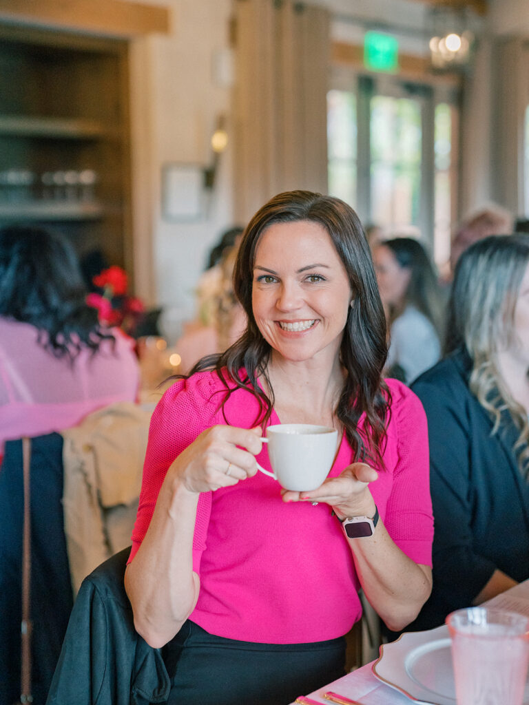 a woman smiling while holding a cup