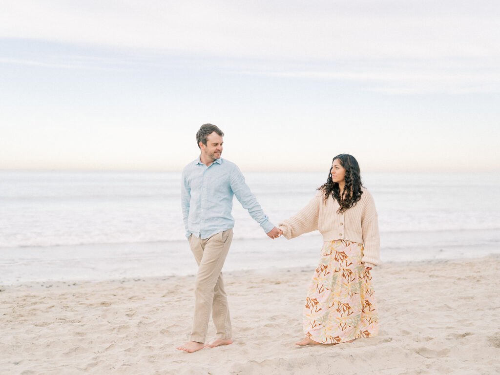 a couple walks hand in hand at pacific beach