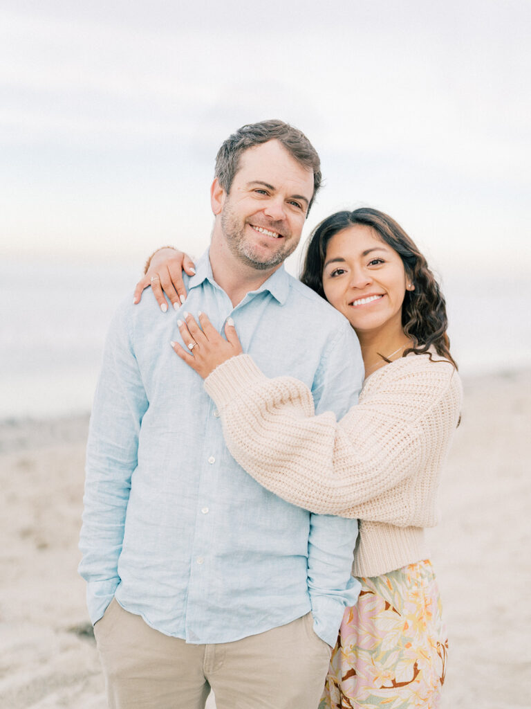 a happy couple embraces, smiling at the camera