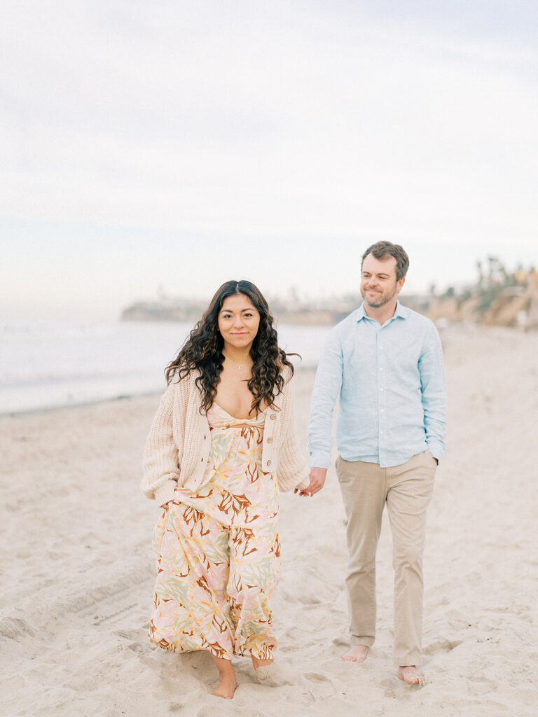 a couple walks hand in hand at pacific beach