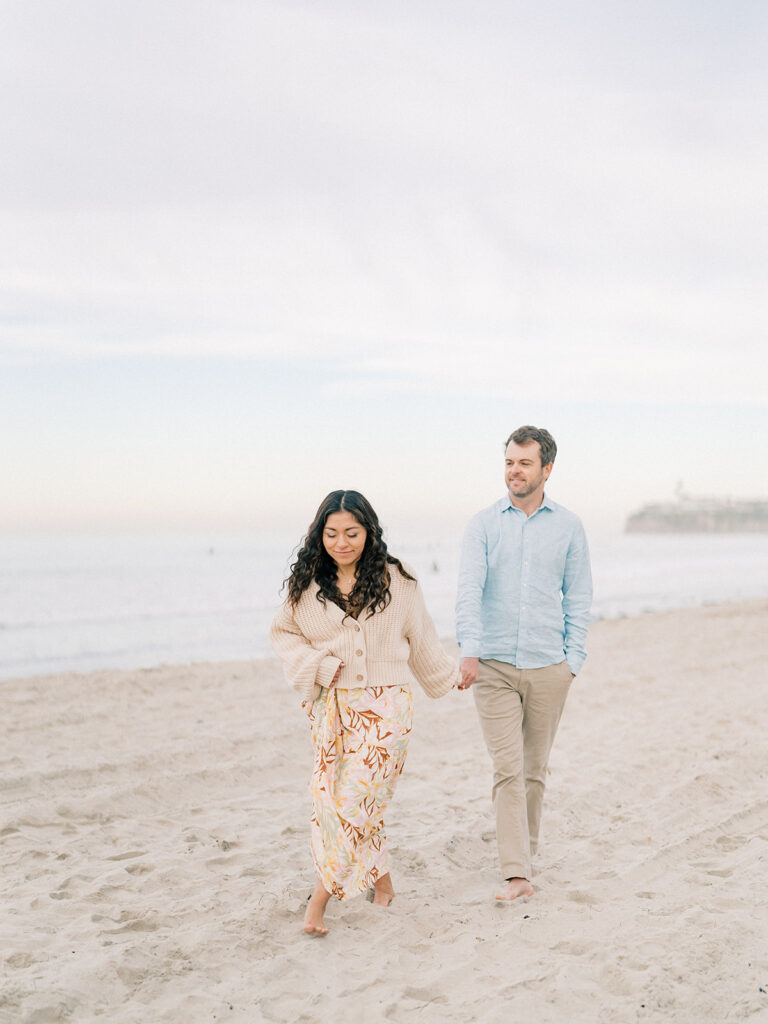 a couple walks hand in hand at pacific beach